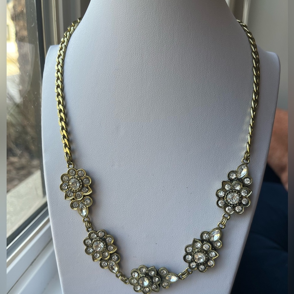 Floral statement necklace in a gold tone setting with round and oval crystals.